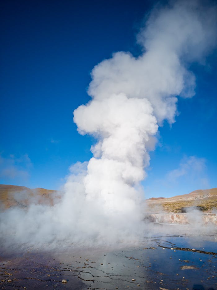 Services Steaming geyser eruption in the barren landscape of Antofagasta, Chile, under a clear blue sky.